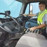 Sweeper driver in cab of sweeper wearing safety vest