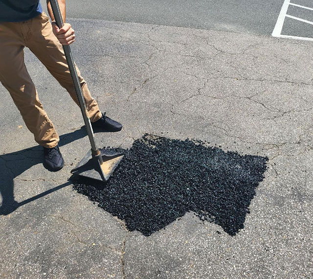 Man tamping down asphalt patch for pot hole repair